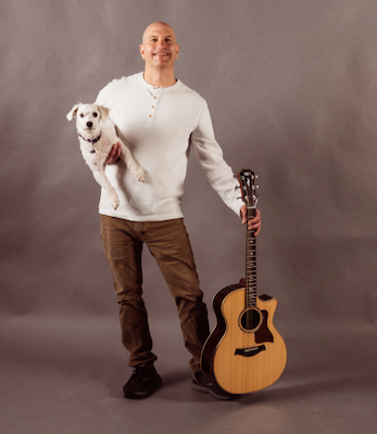 John Onder Photo shows John holding a guitar and his dog